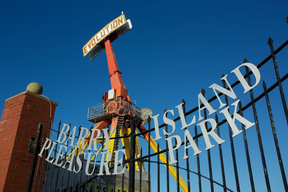 Een bord voor Barry Island Pleasure Park, met een reuzenrad op de achtergrond.