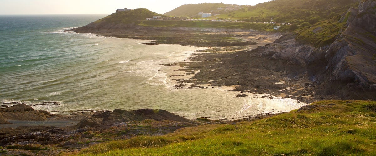 A coastal landscape with rocky cliffs, a beach, and a small settlement on a hill.