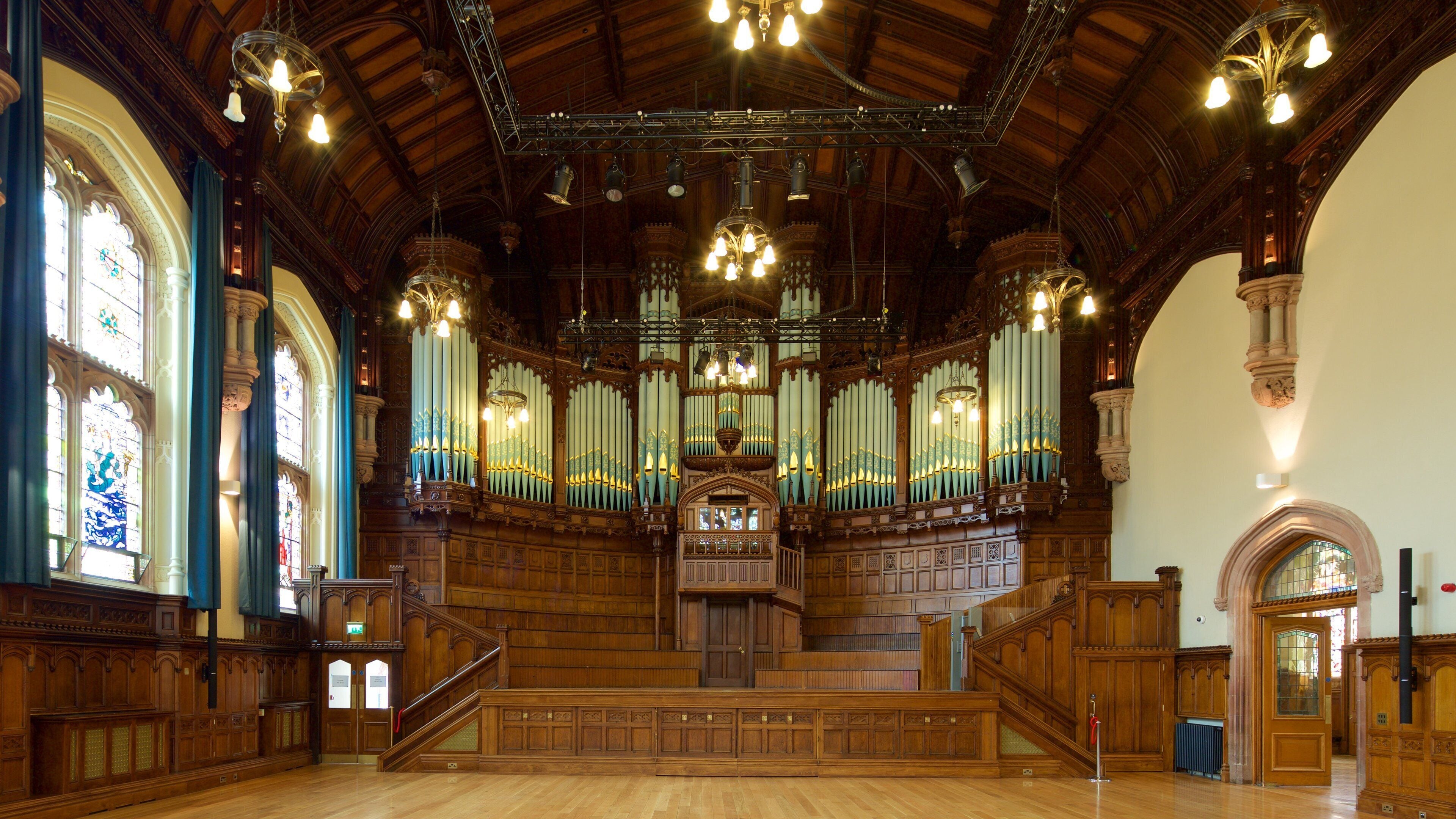 An ornate church interior with wooden pews, stained glass windows, and a large pipe organ.