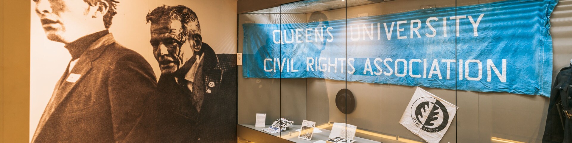 Una vitrina con objetos históricos y un cartel que dice 'Queen's University Civil Rights Association'.