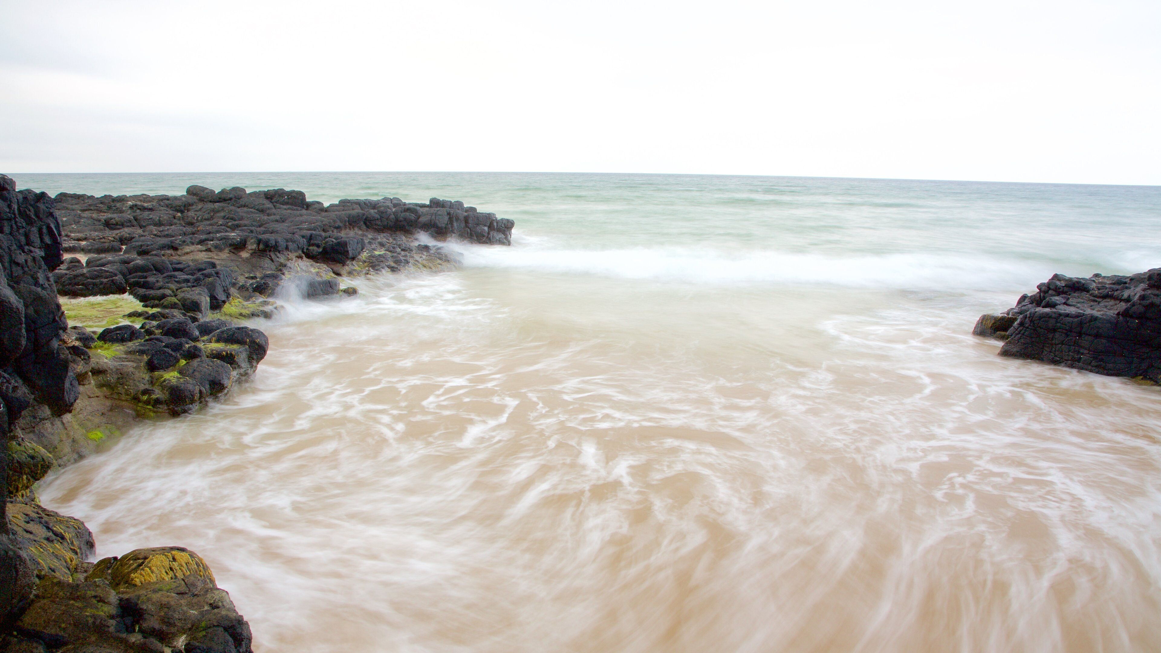 A turbulent sea with waves crashing against dark, rocky shores.