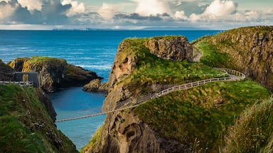 Un paisaje costero con un puente colgante, acantilados rocosos y un mar azul cristalino.