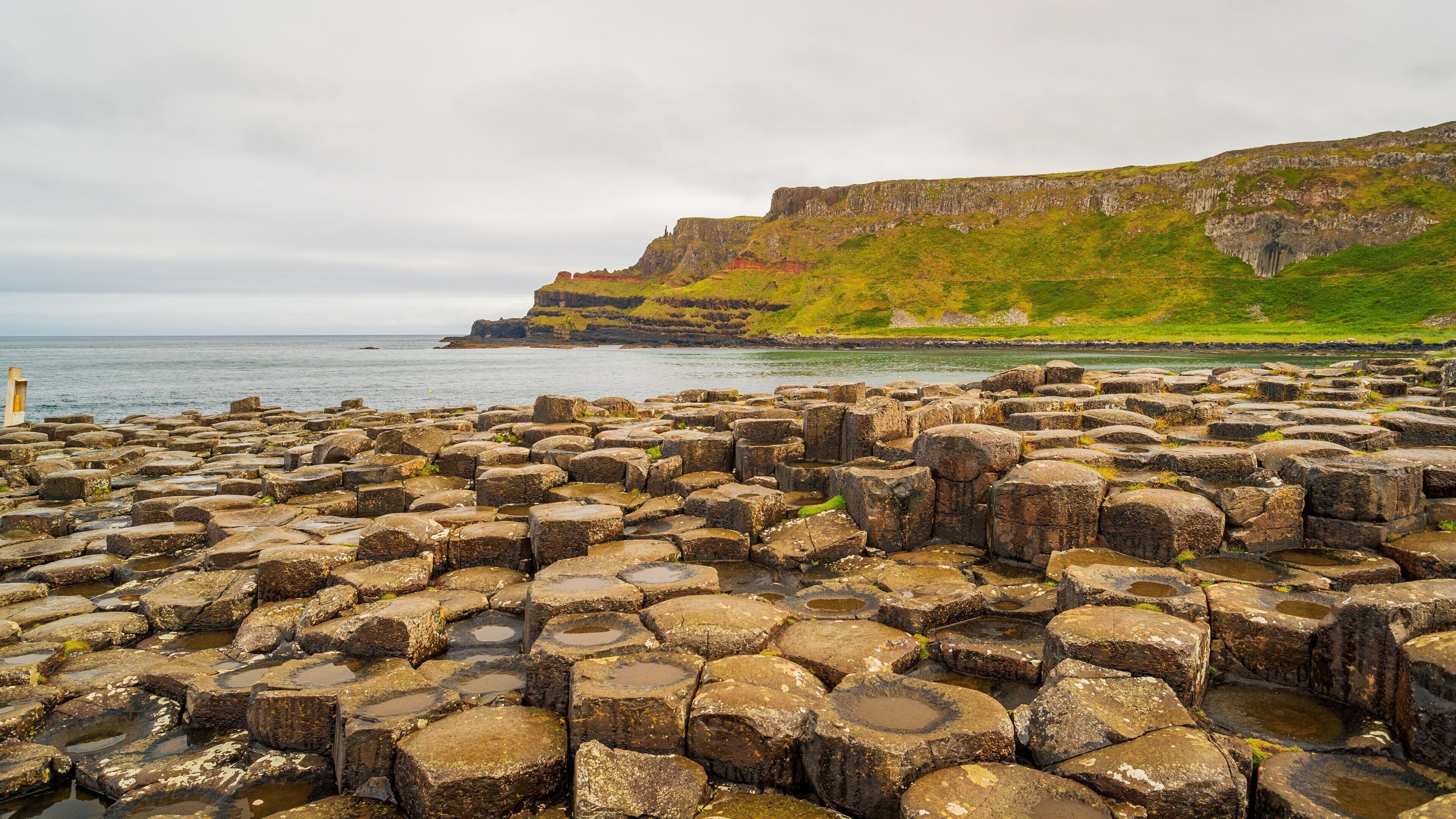 A rocky coastal area with large boulders and cliffs in the background.