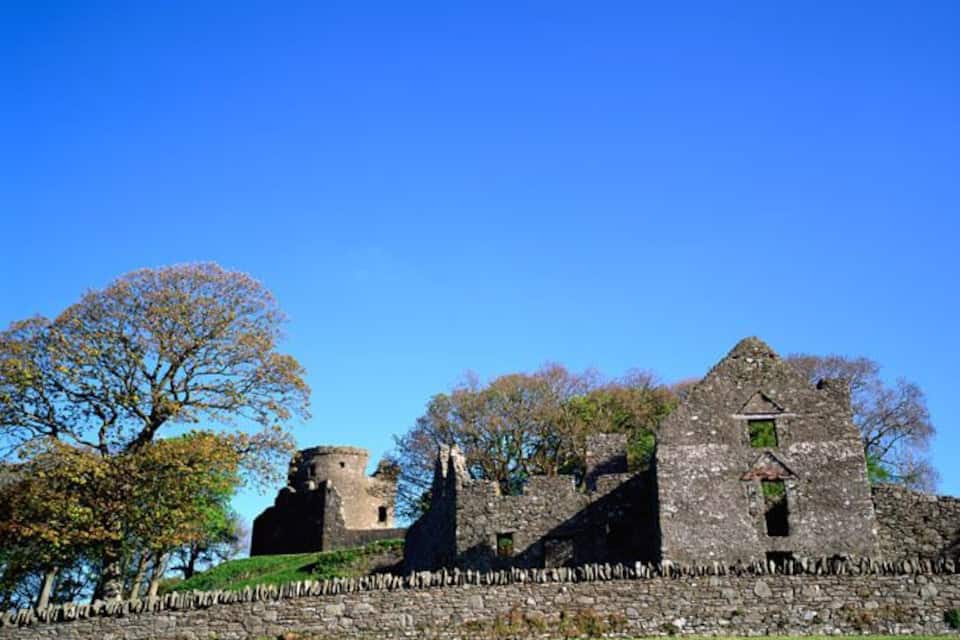 An ancient stone castle with a tower and a ruined wall.