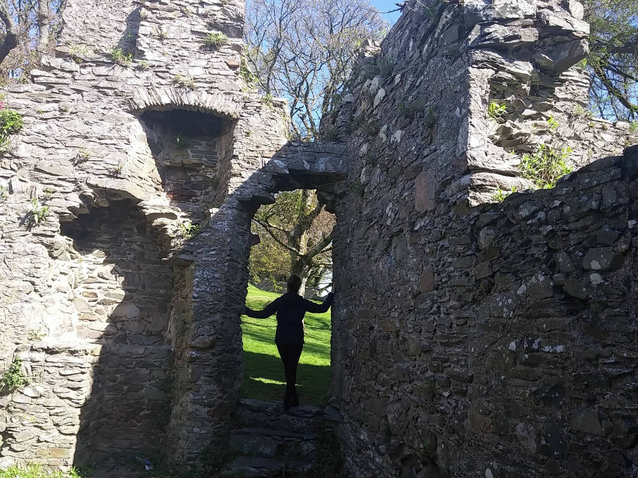 A stone archway in an ancient ruin with a person standing in the center.