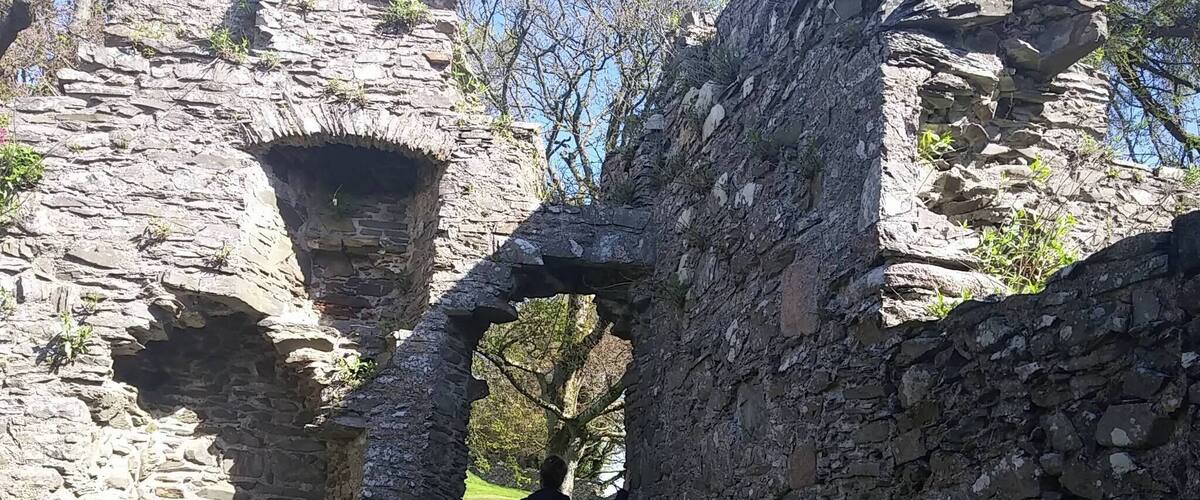 A stone archway in an ancient ruin with a person standing in the center.
