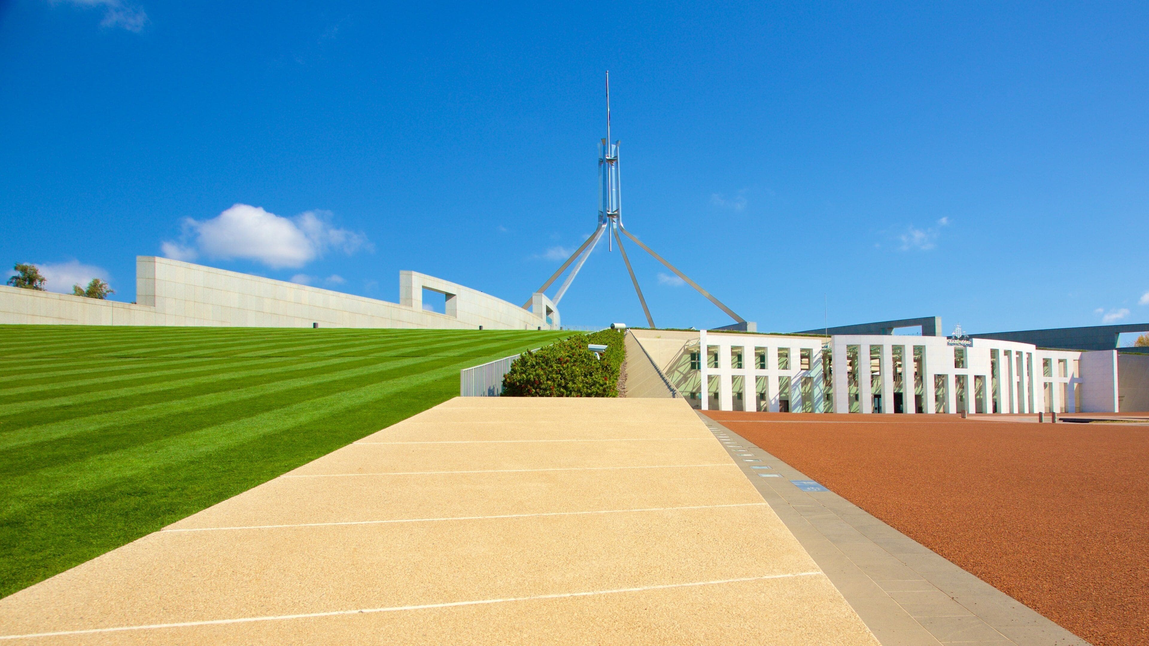 A modern building with a unique triangular roof structure, a well-maintained lawn, and a paved walkway.