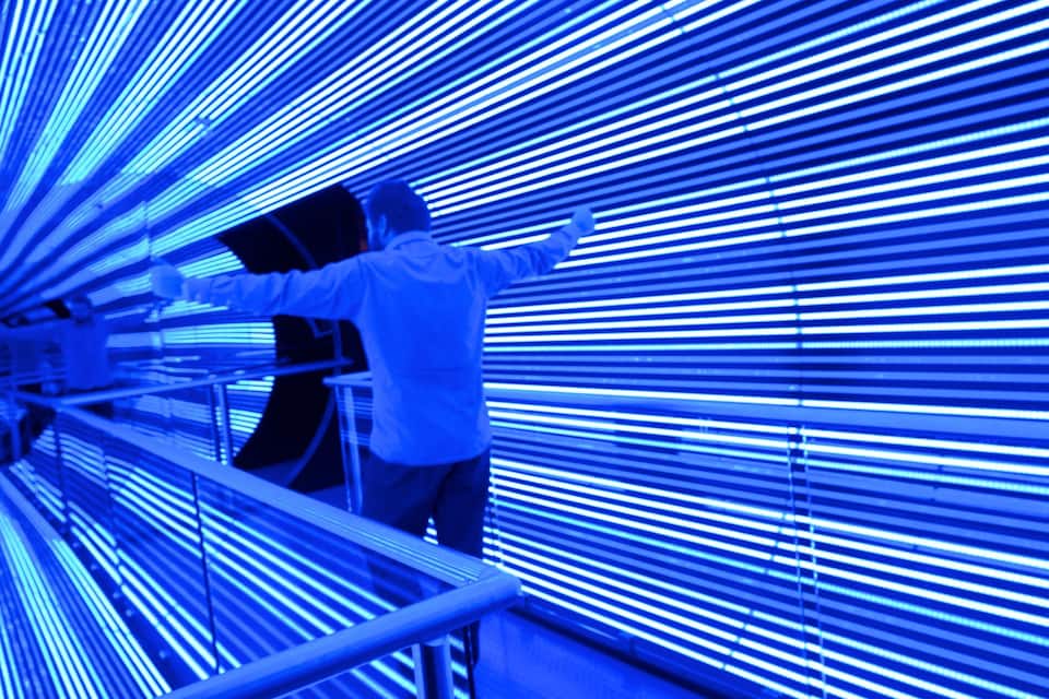 A person in a white coat working with a large blue-lit structure.