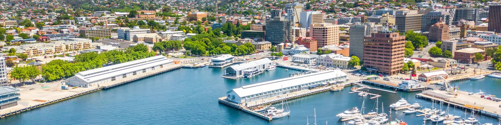 A coastal cityscape with a marina, buildings, and a mountain in the background.