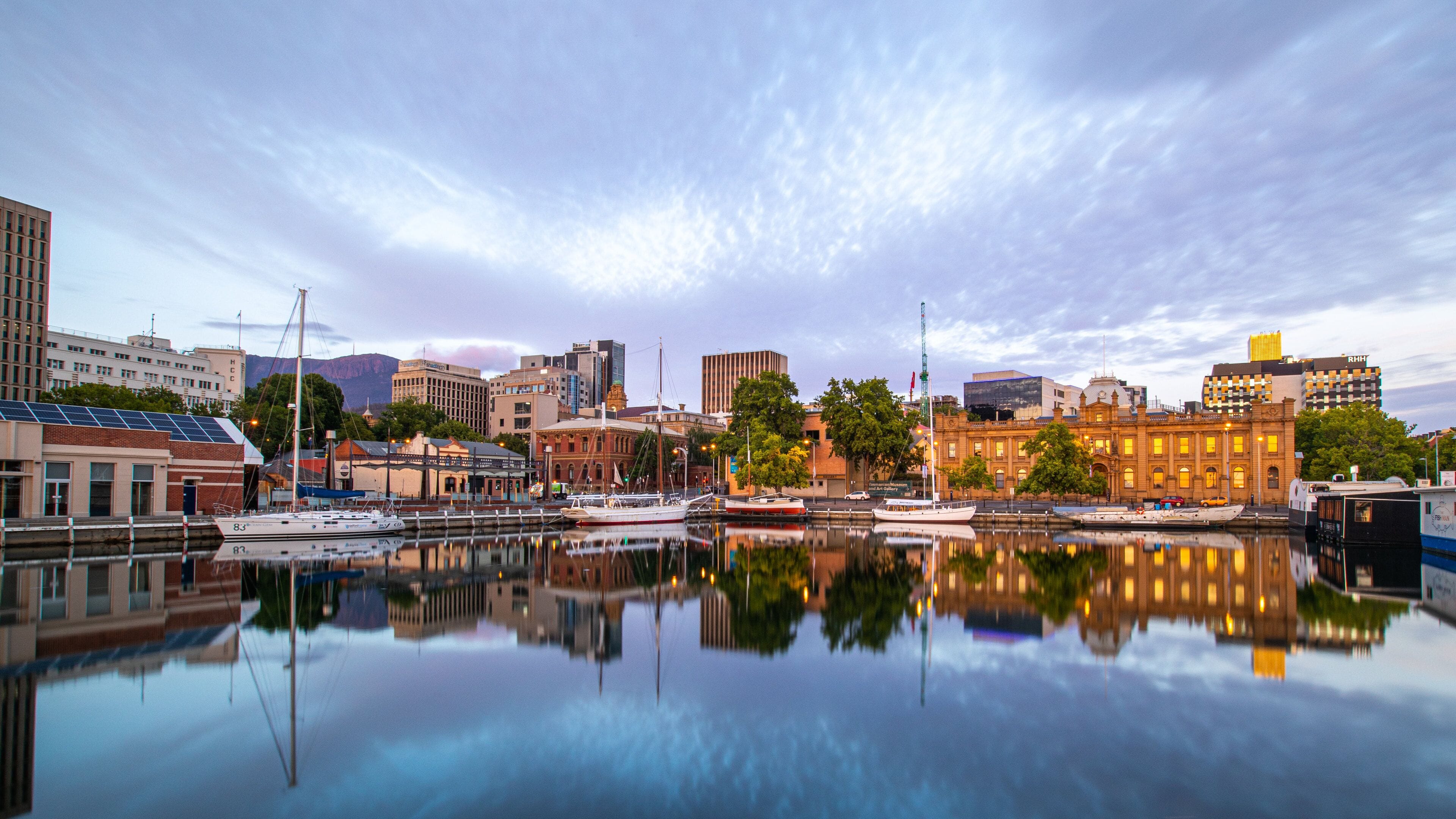 A waterfront cityscape with a calm harbor, historic buildings, and a clear sky.