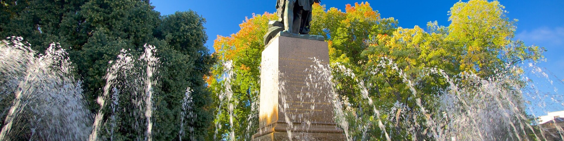 A statue with water jets in a park.