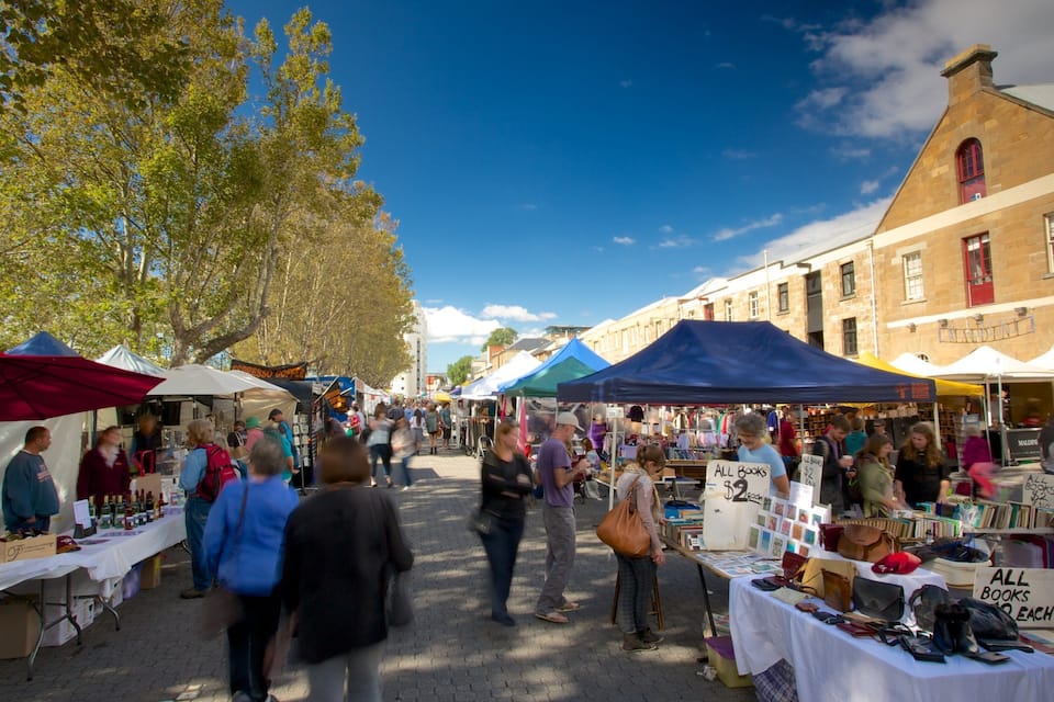A busy outdoor market with various stalls selling books and other items.