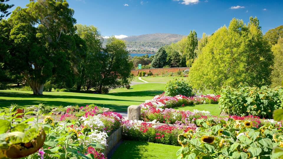 A lush garden with vibrant flowers, a well-maintained lawn, and a distant view of a town and mountains.