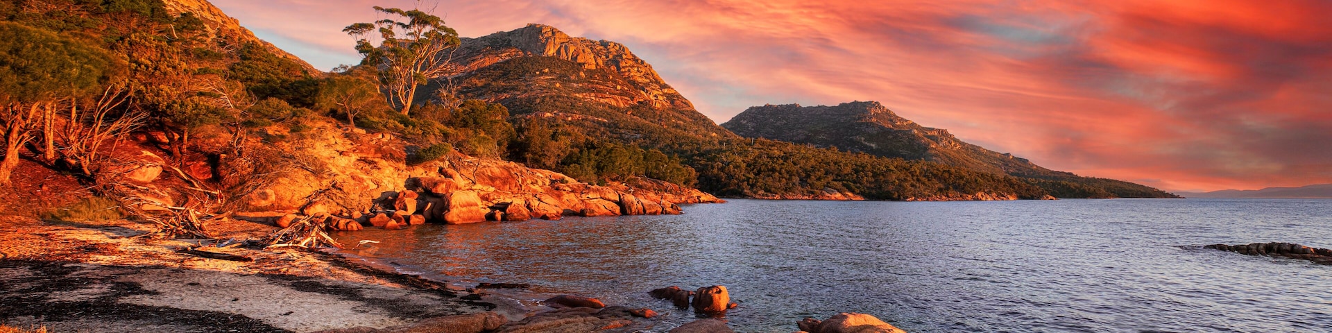 Un paisaje costero con afloramientos rocosos, un mar tranquilo y un cielo al atardecer.