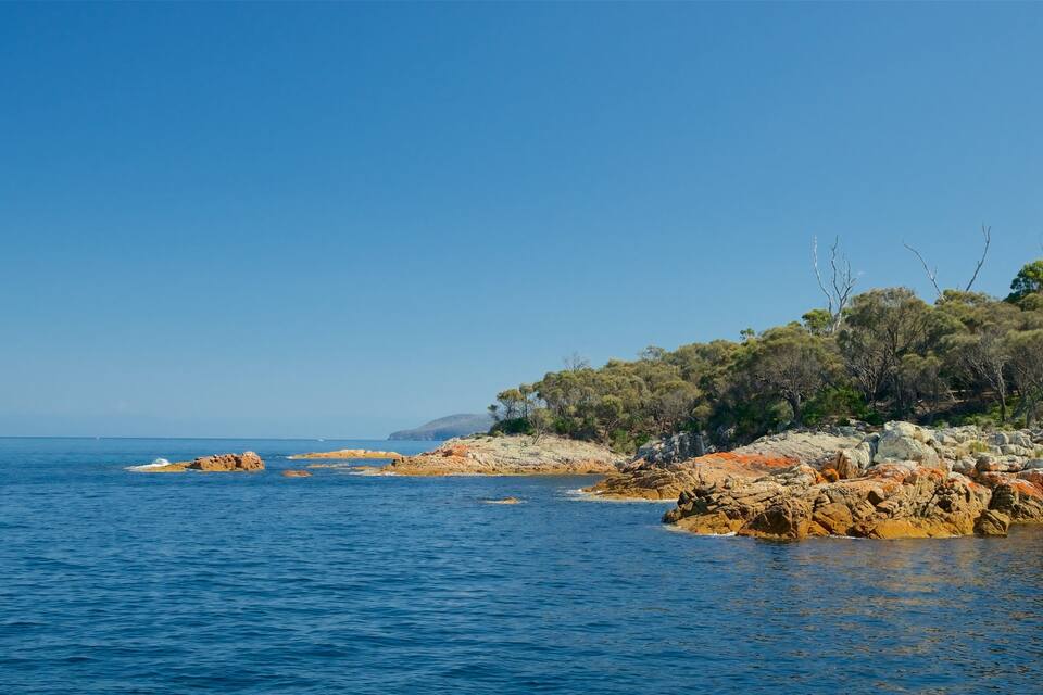 Un paisaje costero con afloramientos rocosos, mar azul cristalino y vegetación escasa.