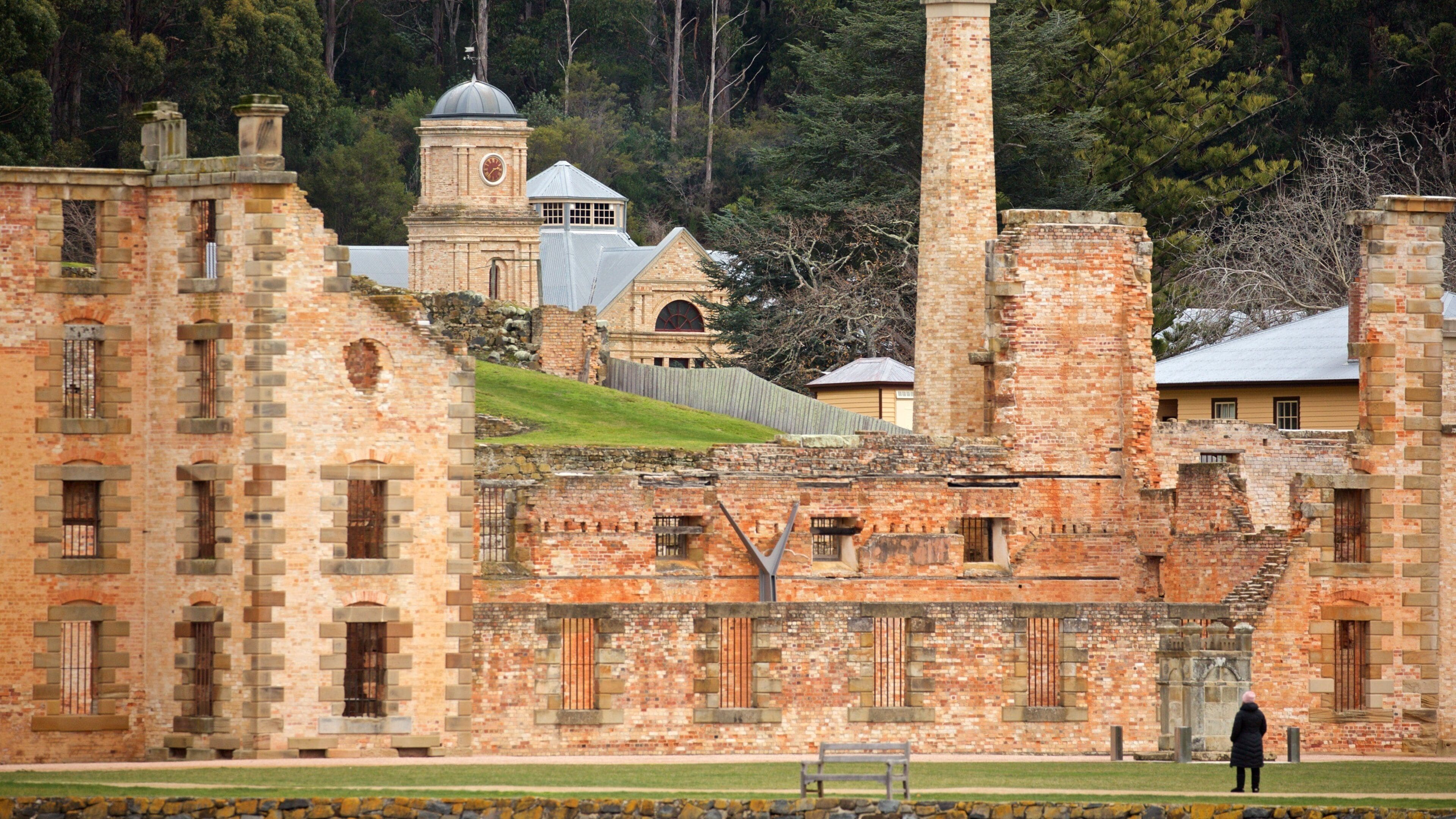 A historic building complex with brick structures, a clock tower, and a large chimney.