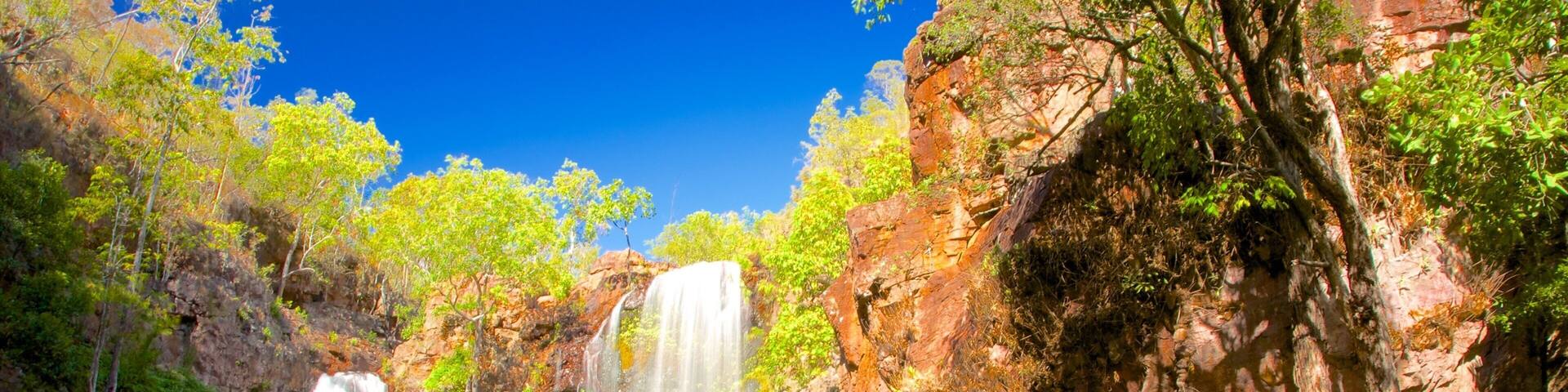 A waterfall cascading into a pool surrounded by rocky cliffs and lush greenery.