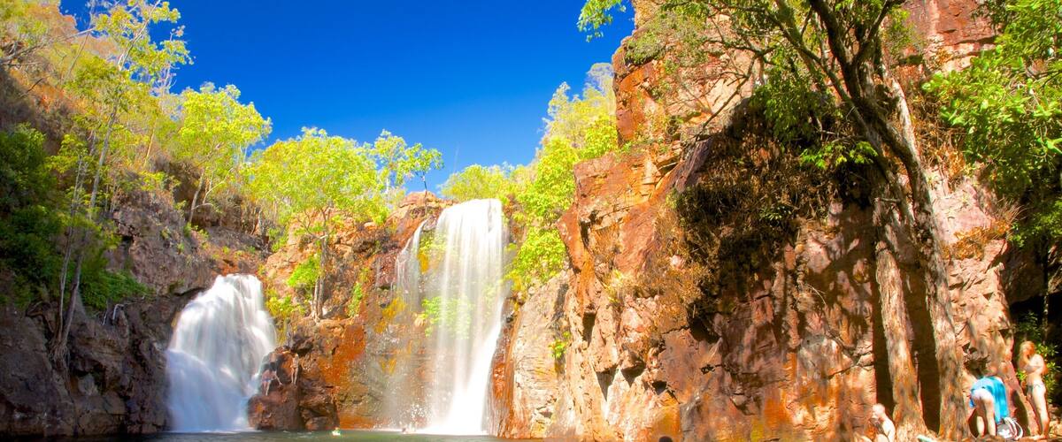 A waterfall cascading into a pool surrounded by rocky cliffs and lush greenery.