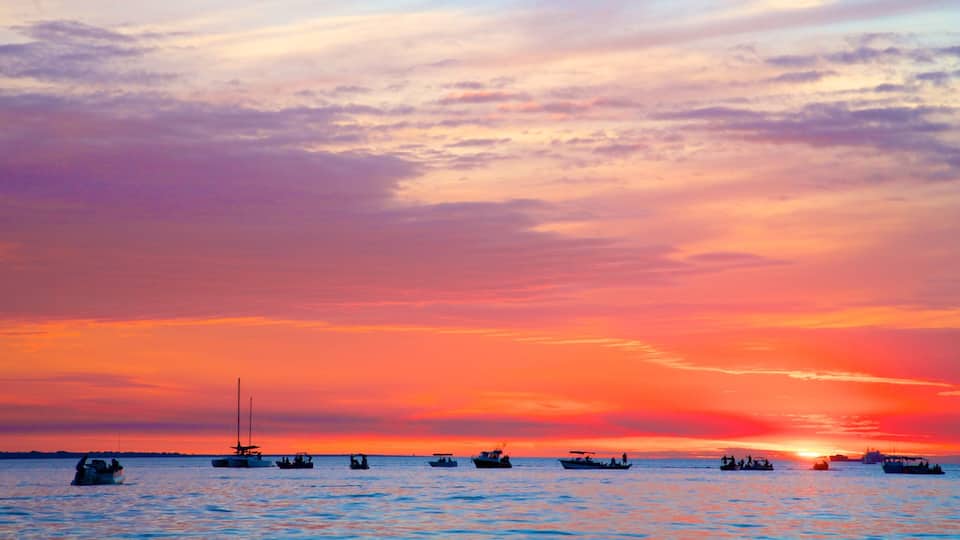 A sunset over a body of water with several boats.