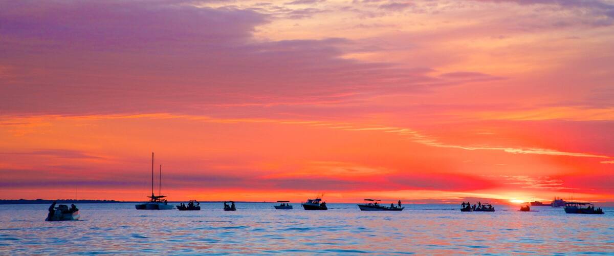 A sunset over a body of water with several boats.