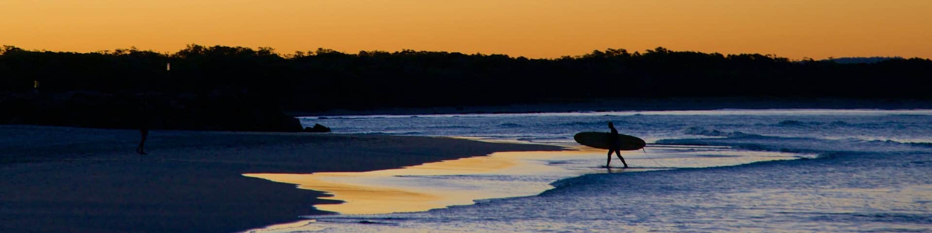 Noosa Beach which includes a beach, a sunset and surfing