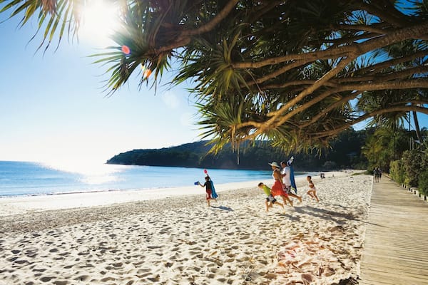 Noosa Beach showing tropical scenes and a sandy beach as well as a family