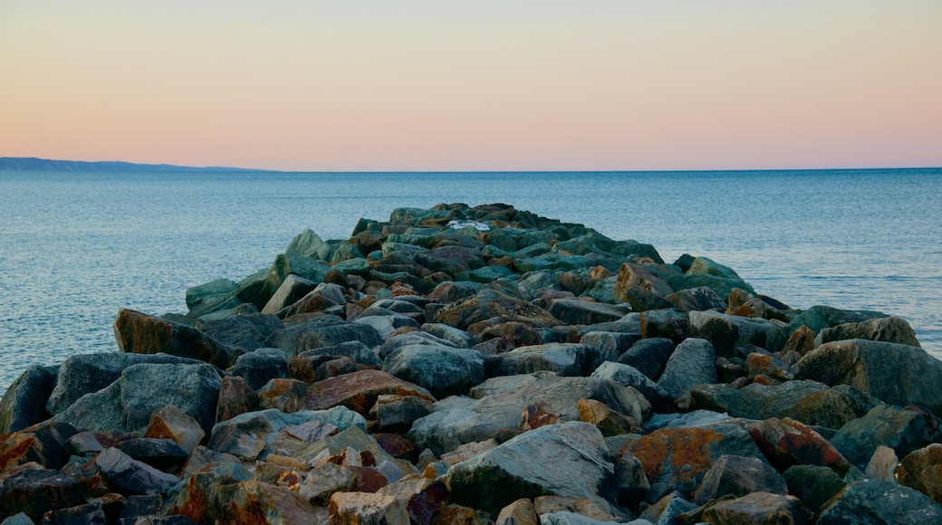 Noosa Beach which includes rocky coastline and a sunset