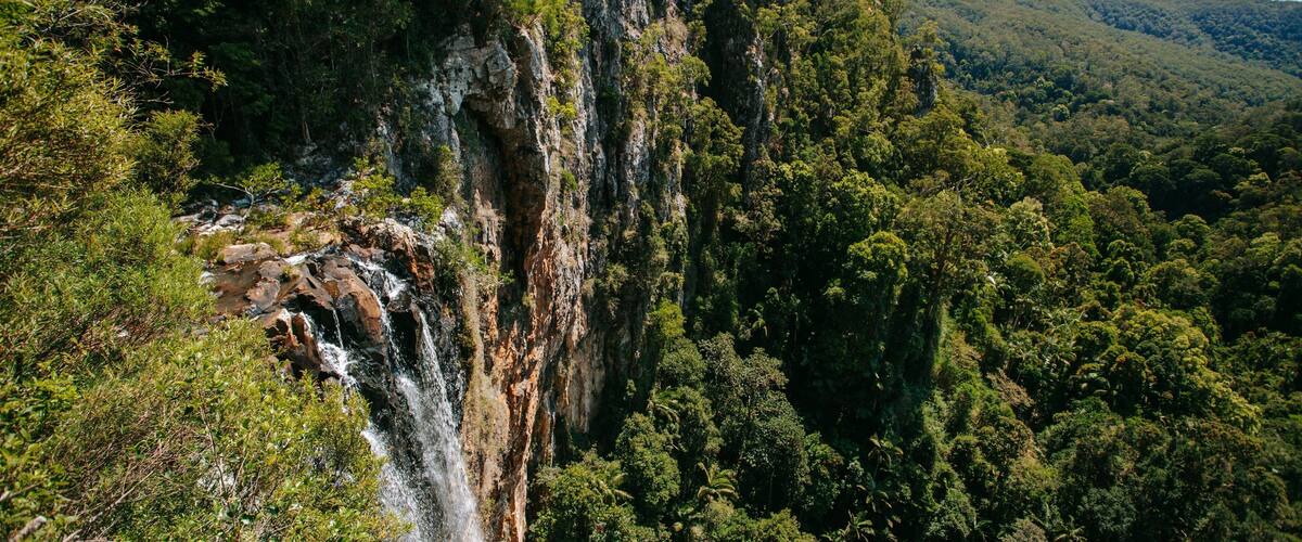A waterfall cascading down a steep cliff surrounded by dense forest.