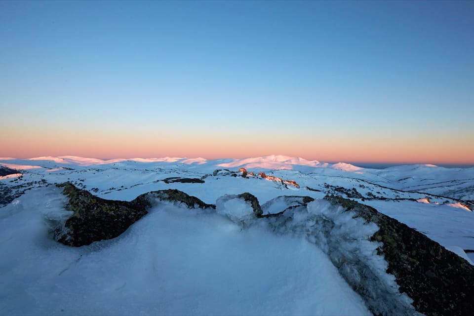 A snow-covered mountain range at sunset.