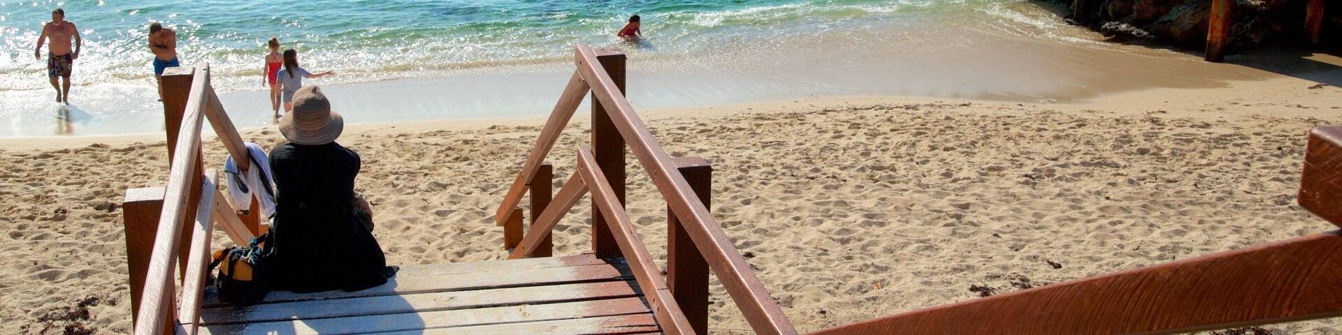 Prevelly Beach featuring a bay or harbor and a sandy beach as well as a small group of people