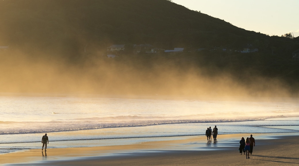 Main Beach featuring mist or fog and a beach as well as a small group of people