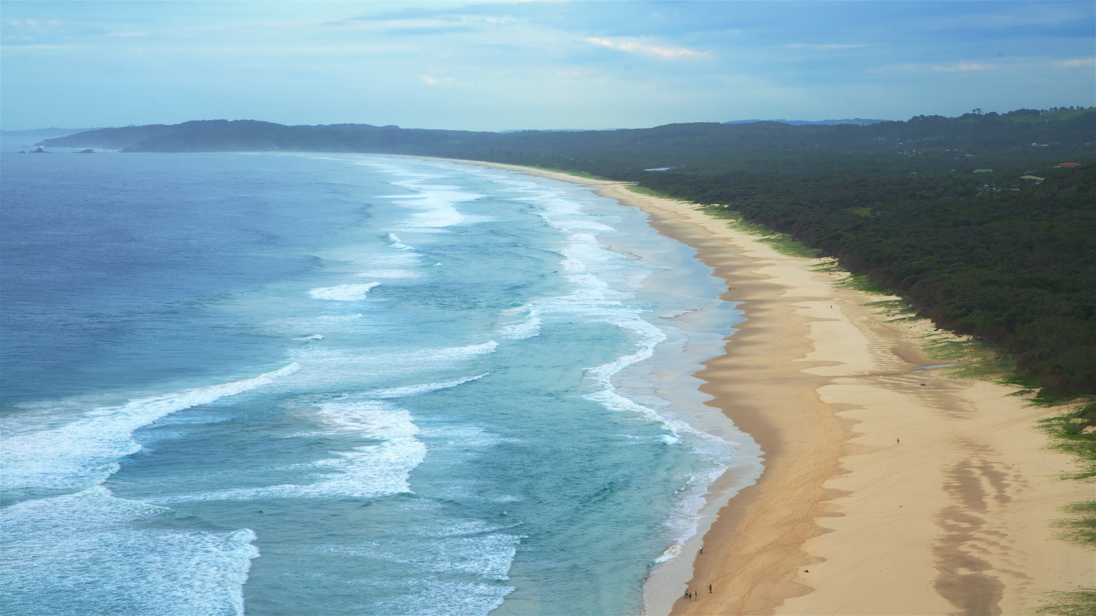 A coastal landscape with a sandy beach and ocean waves.