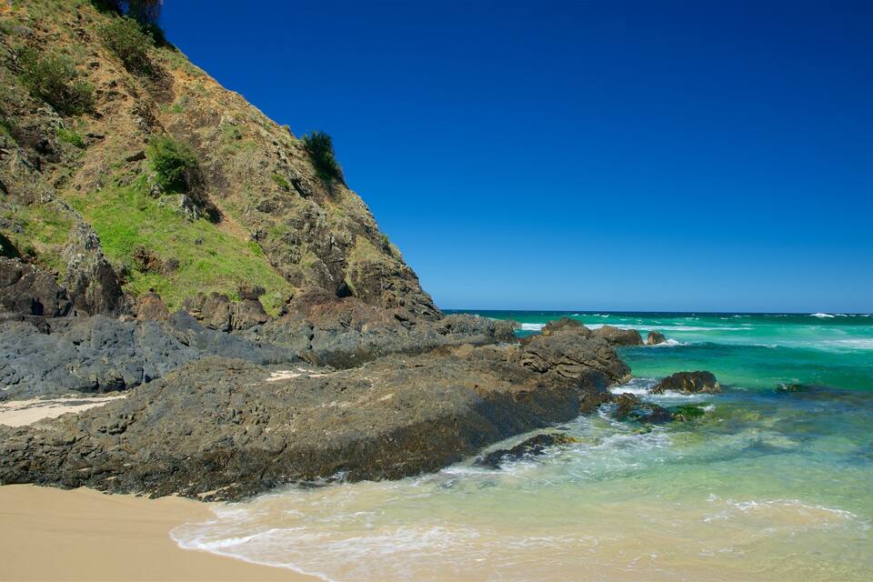 A rocky coastline with clear turquoise waters and a sandy beach.