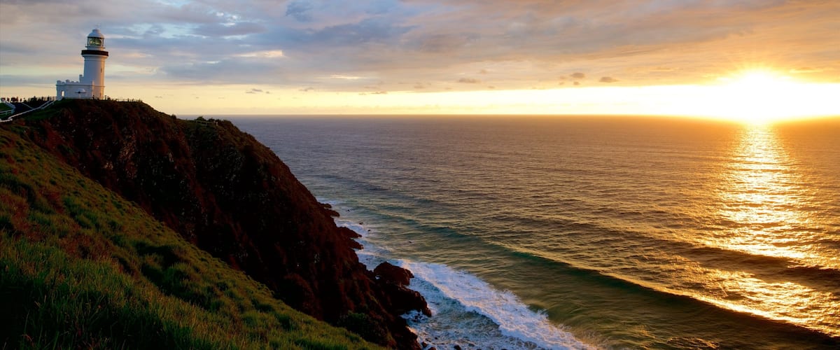 Cape Byron Lighthouse showing a sunset and rugged coastline