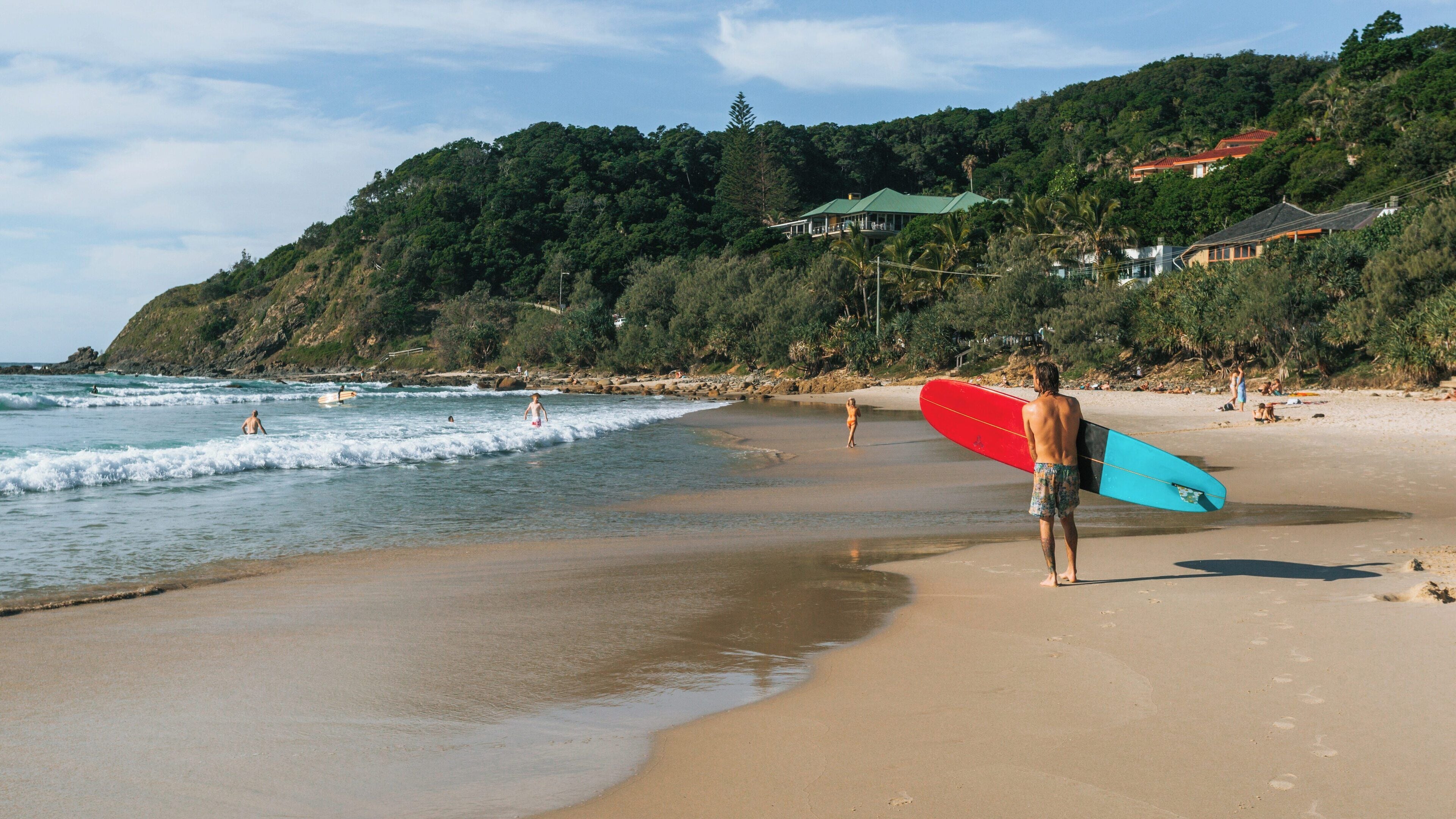 Surfing at Wategos Beach in Byron Bay on a sunny day with clear skies and gentle waves welcoming beachgoers