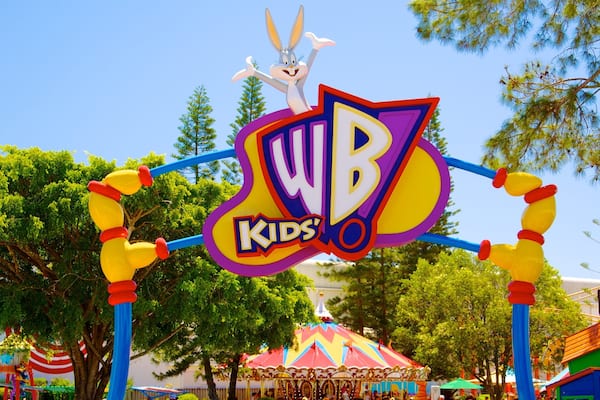 A WB Kids' sign with a rabbit mascot, surrounded by trees and carnival rides.