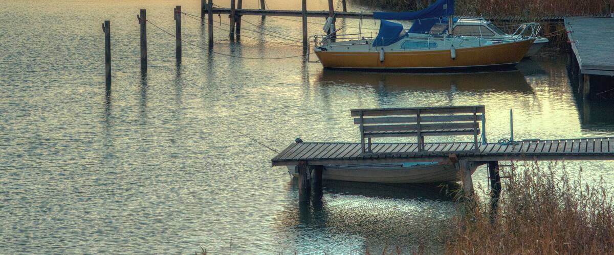 A sunset over a calm lake with a dock and a small boat.