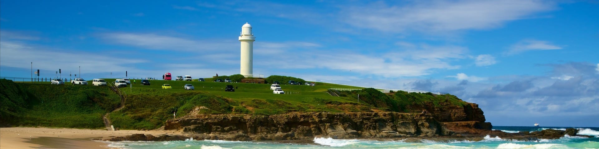 A lighthouse on a grassy cliff by the ocean.