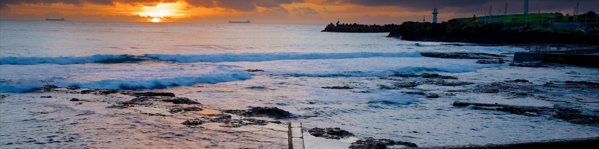 Wollongong North Beach mostrando una playa, un atardecer y vistas de una costa