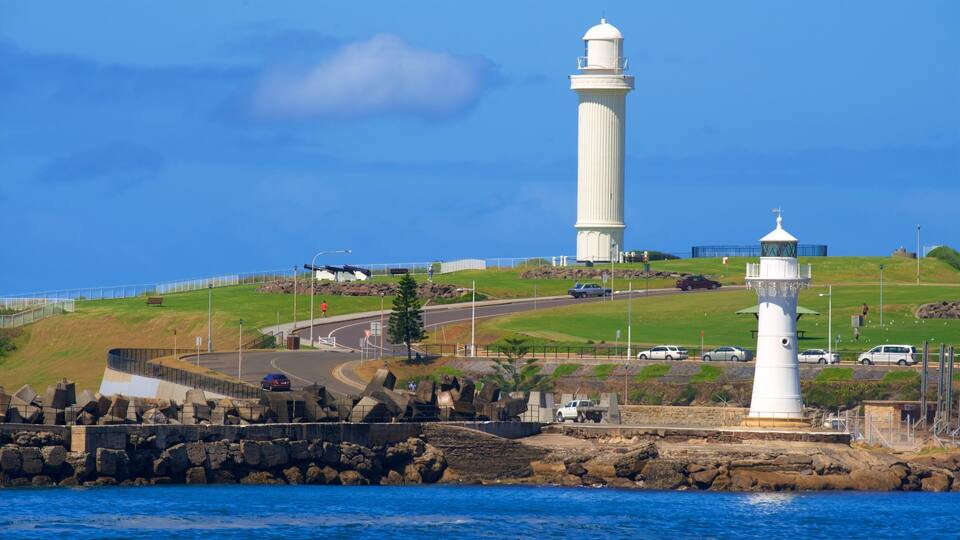 Un phare, une route côtière et une colline verdoyante bordée d’une côte rocheuse.