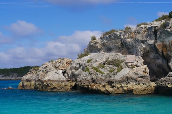 Boulders of rocks hiding the Thunderball Grotto in the blue waters of Exuma Cays, Bahamas. The location is a popular destination and has been used for filming several movies.