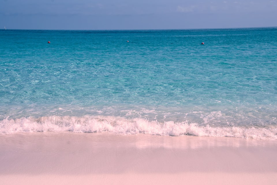 Une plage à l’eau turquoise et au sable blanc.