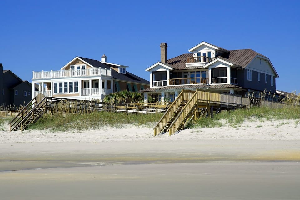 Casas frente al mar con terrazas de madera y escaleras que dan a la playa.