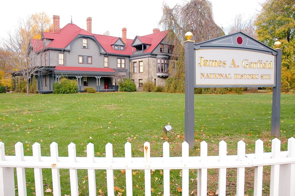 A historic house with a red roof and a sign reading "James A. Garfield National Historic Site".