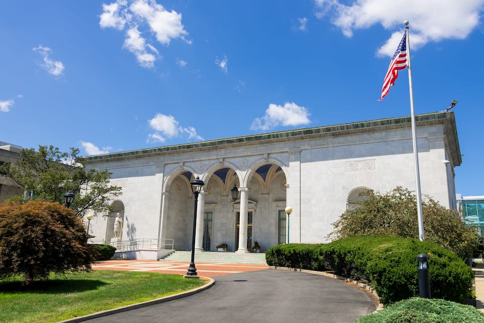 Un gran edificio blanco con columnas y una bandera estadounidense.