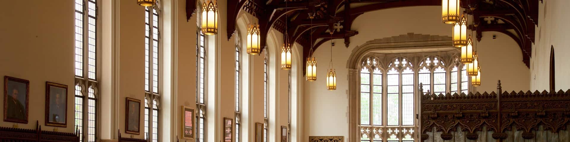 A library with tall windows, wooden bookshelves, and ornate chandeliers.