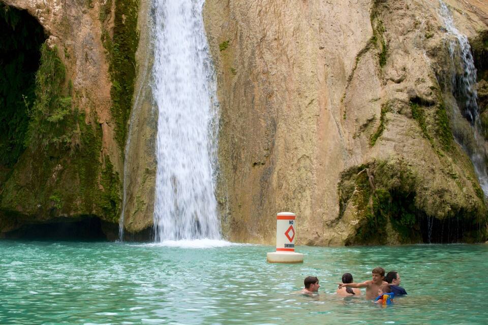 A waterfall, clear water, and a no swimming sign.