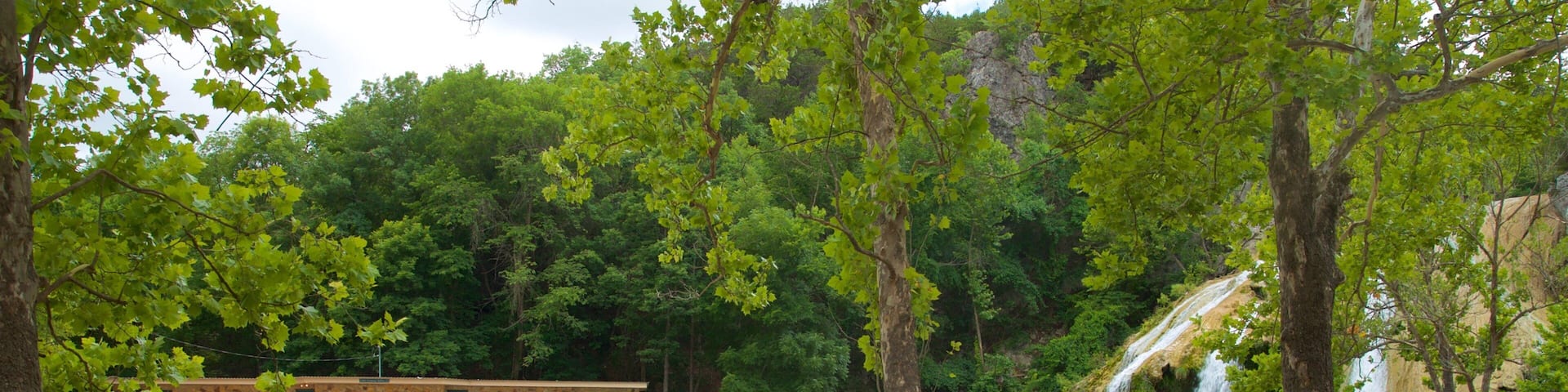 A natural water park with a pool, waterfalls, and a wooden deck.