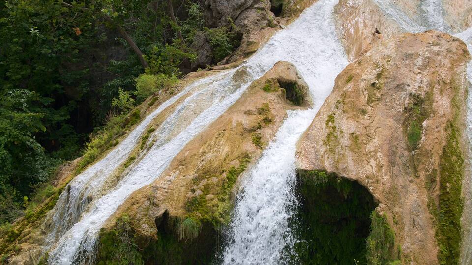A multi-tiered waterfall surrounded by dense forest.