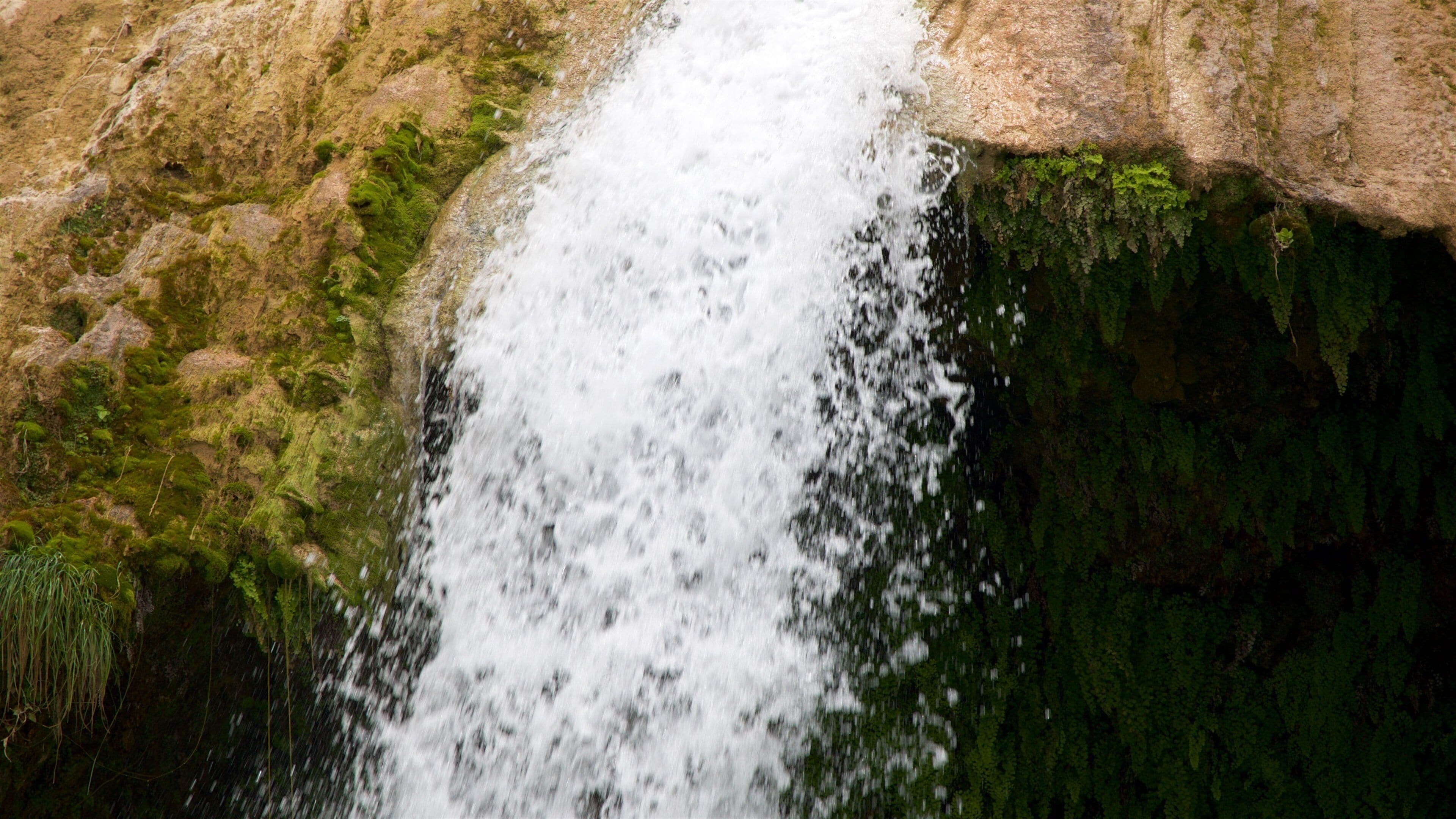 A waterfall cascading over moss-covered rocks.